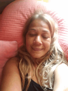 a woman with blonde hair is laying on a pink pillow