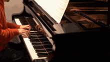 a person playing a piano with a sheet of music on top of it