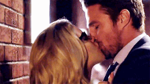 a man in a suit and tie is kissing a woman on the cheek .