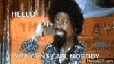 a man with a beard is talking on a telephone and says `` hello you can 't call nobody '' .