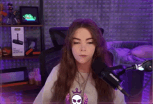 a woman is sitting in front of a microphone with her eyes closed and a skull necklace .