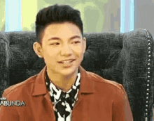 a young man is sitting in a chair and smiling at the camera .