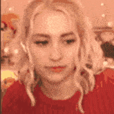 a woman wearing headphones and a red sweater is making a funny face .