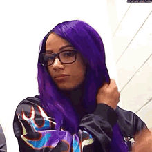 a woman with purple hair and glasses is wearing a jacket with flames on it .