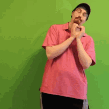 a man in a pink under armour shirt is standing in front of a green screen