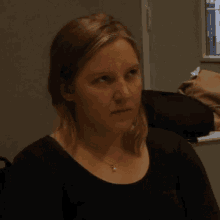 a woman wearing a black shirt and a necklace is looking to the side