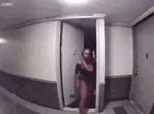 a woman in a black dress is walking through a doorway .