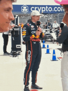 a man in a red bull suit stands in front of a crypto.com banner