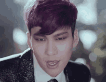 a young man with purple hair is wearing a suit and tie
