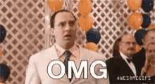 a man in a suit and tie is standing in front of a bunch of balloons and says omg .