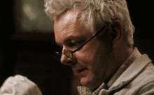 a man wearing glasses and a bow tie looks down