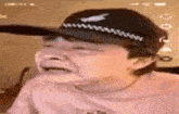 a young boy wearing a hat is crying while looking at his phone .
