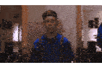 a boy in a blue shirt and suspenders is looking at himself in the mirror