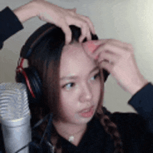 a woman wearing headphones is using a sponge on her forehead .