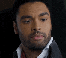 a close up of a man 's face with a beard and a white shirt