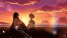 a couple of girls standing on a beach holding hands at sunset