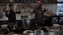 two men in a kitchen with one wearing a shirt that says ' a few cents ' on it