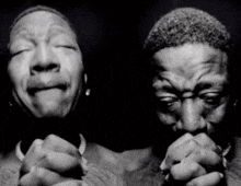 a black and white photo of two men with their hands folded