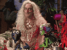 a man in a wig is standing next to two muppet characters