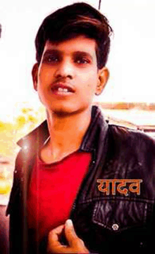 a young man wearing a red shirt and a black jacket with the word yadav written on the back .