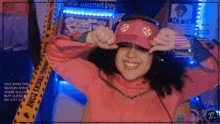 a woman wearing a pink hat and headphones stands in front of a warning tape that says halloween