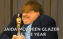 a man in a suit is holding an oscar statue and says jaida mcqueen glazer of the year ..