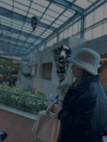 a woman wearing a white hat and a black jacket looks at her phone