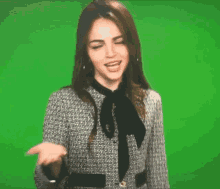 a woman wearing a bow tie is making a funny face against a green screen