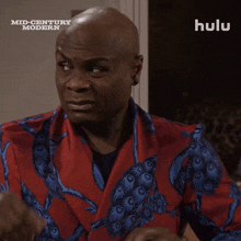a bald man is wearing a red and blue jacket with a hulu logo in the background