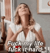 a woman is sitting at a table with her hands in her pockets and says `` fuck my life fuck it hard '' .