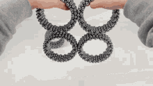 a person is holding a bunch of metal balls in their hands that look like a snake