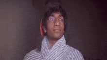 a young man wearing glasses and a striped shirt is looking up at the camera .