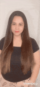 a woman with long hair and a black shirt is standing in front of a wall .