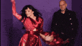 a woman in a red dress is dancing next to a man