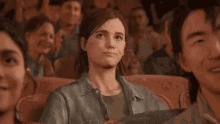 a woman is sitting in a crowd of people watching a movie and clapping her hands .