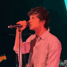 a man is singing into a microphone on a stage in a dark room .