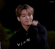 a young man wearing a black vann sweatshirt gives a thumbs up sign