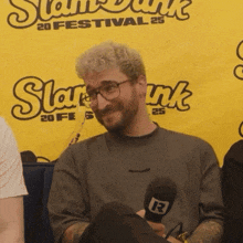 a man is holding a microphone in front of a banner that says slam dunk
