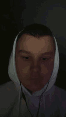 a young man wearing a white hoodie and earphones looks at the camera