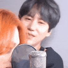 a man with red hair is kissing another man on the cheek in front of a microphone .