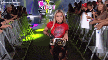 a woman in a red shirt is holding a wrestling belt in front of a crowd with a sign that says crazy about it