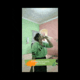 a woman in a green shirt is dancing in a room with a sign that says edakenlah guy 's soloyong