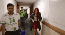 a man wearing a holiday inn shirt is walking down a hallway with a woman .