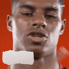 a close up of a man 's face with a piece of paper between his mouth and his nose .