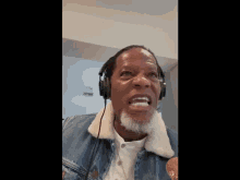 a man wearing headphones and a denim jacket with a white collar