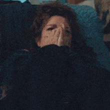 a woman laying on a couch with her eyes closed and her hands on her face