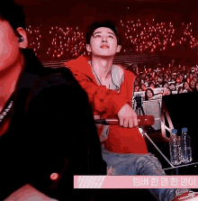 a man in a red jacket stands in front of a crowd