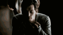 a man is sitting in a dark room with his hands folded and his head down .