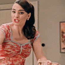 a woman in a red and white dress stands in front of a painting