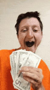 a man is holding a bunch of 5 dollar bills in his hand